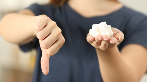 Front view close up of a woman hand holding sugar cubes with thumbs down at home